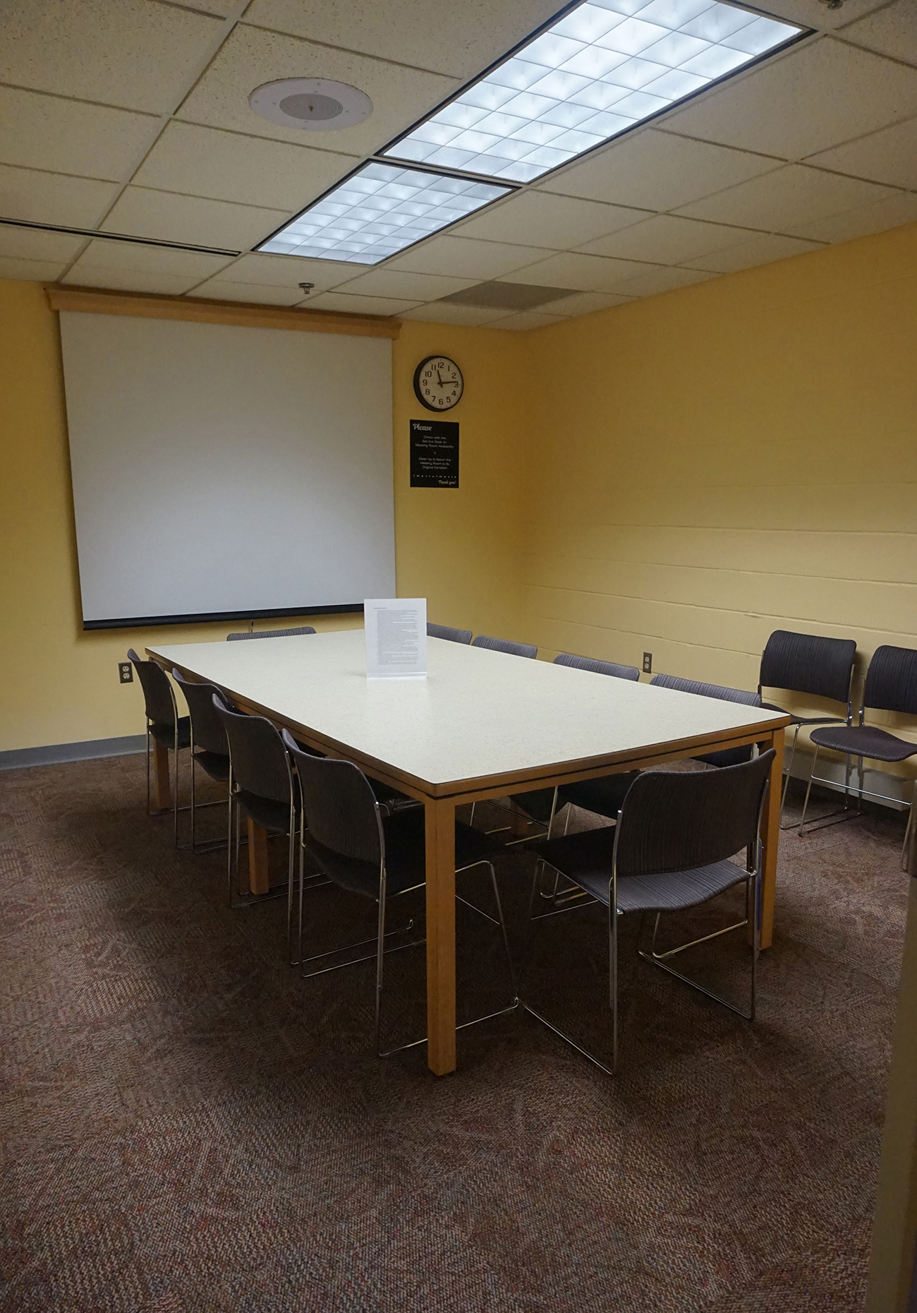 Rectangular table with chairs, white screen at front
