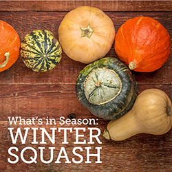 Different types of winter squash on a wooden tabletop