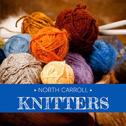 Knitting needles and yarn rolls on a dark tabletop