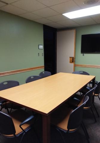 Small room with rectangular table and multiple chairs 