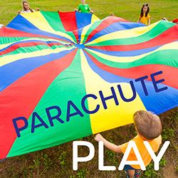 A group of children holding a multicolored parachute cloth