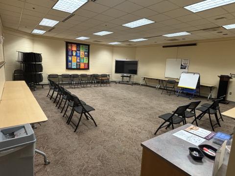 Large open room with carpet with tables lining the walls.