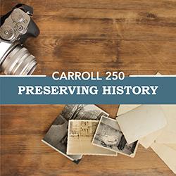 A wooden table seen from above with vintage photographs and a 35mm film camera.