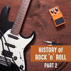 Black and white Fender style electric guitar with cables and orange effects pedal seen from above on a wooden surface.