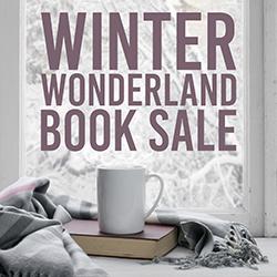 A white mug, book, and gray scarf on a windowsill with snowy trees outside.