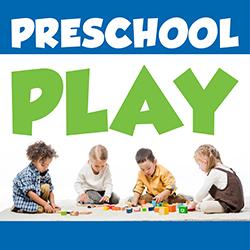 Four preschoolers playing with blocks on a beige carpet.
