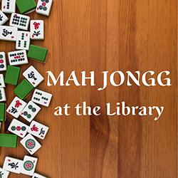 Assorted Mah Jongg tiles on the left of a wooden tabletop seen from above.