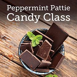 A bowl of dark chocolate chunks and fresh peppermint on a wooden table