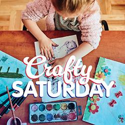 View from above of a little girl working with paper and paints on a wooden table