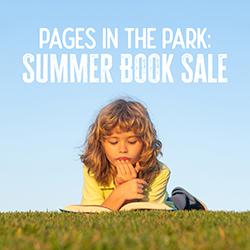 Young girl reading a book in the grass with blue sky above.
