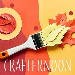 Paintbrush painting out paper autumn leaves over a cut paper background in yellows and oranges.