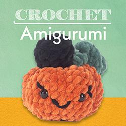 A crocheted amigurimi pumpkin in orange, green, and black.